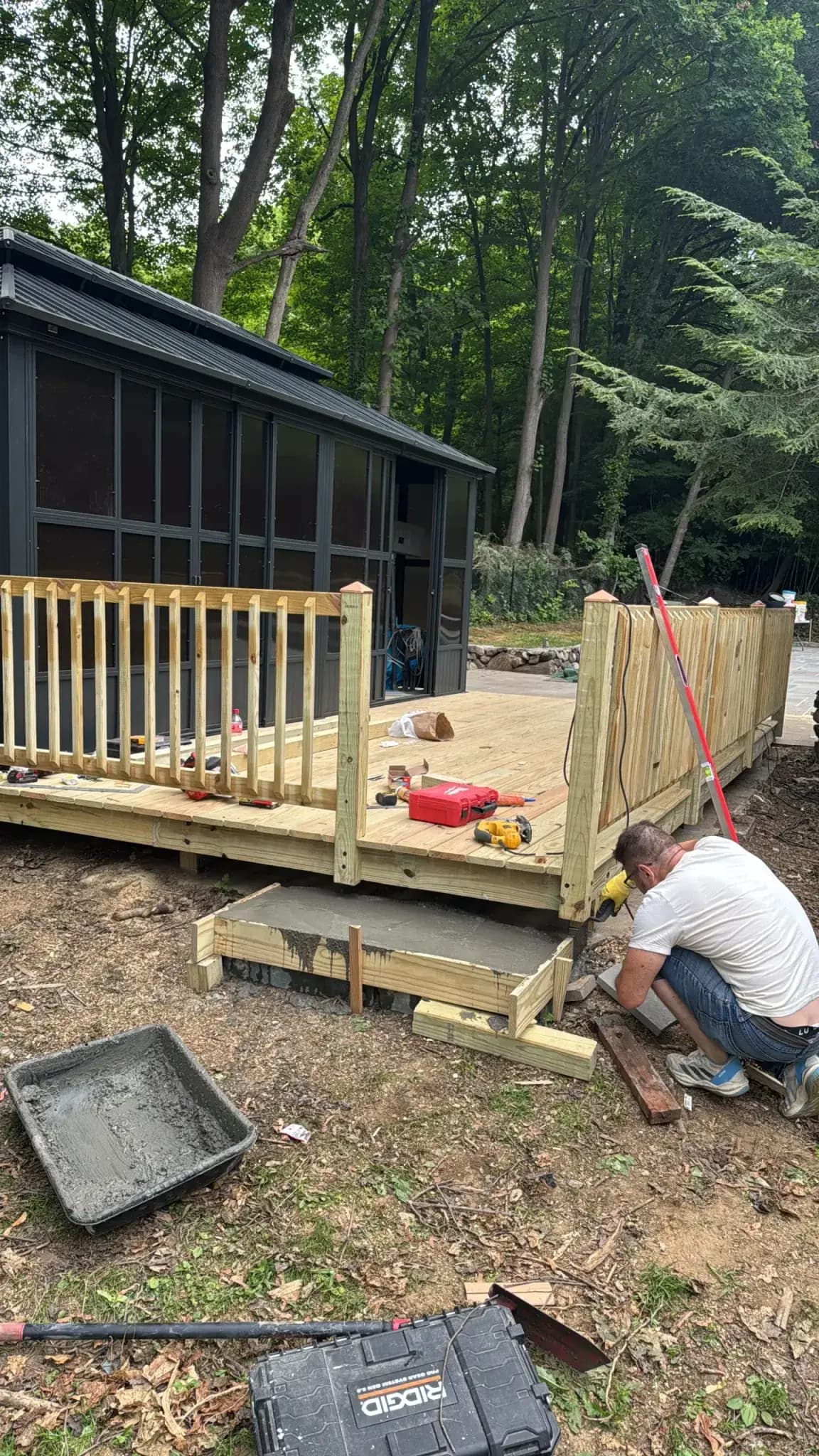 Carpenter building the deck platform and railing posts for a screened gazebo - Greater Homes Solutions LLC