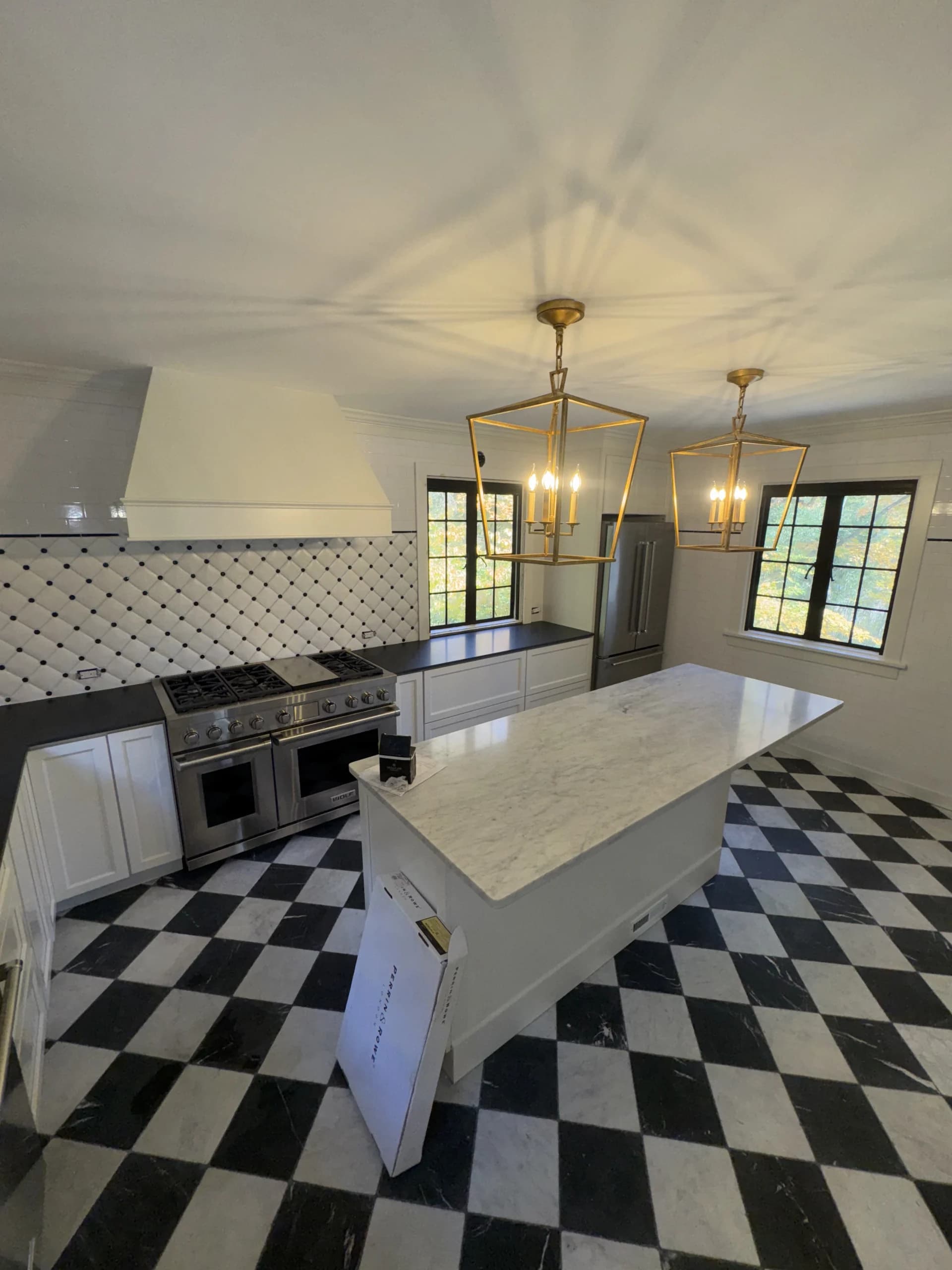 Marble island and range hood in a kitchen with a black and white checkered floor - kitchen remodeling by Greater Homes Solutions LLC