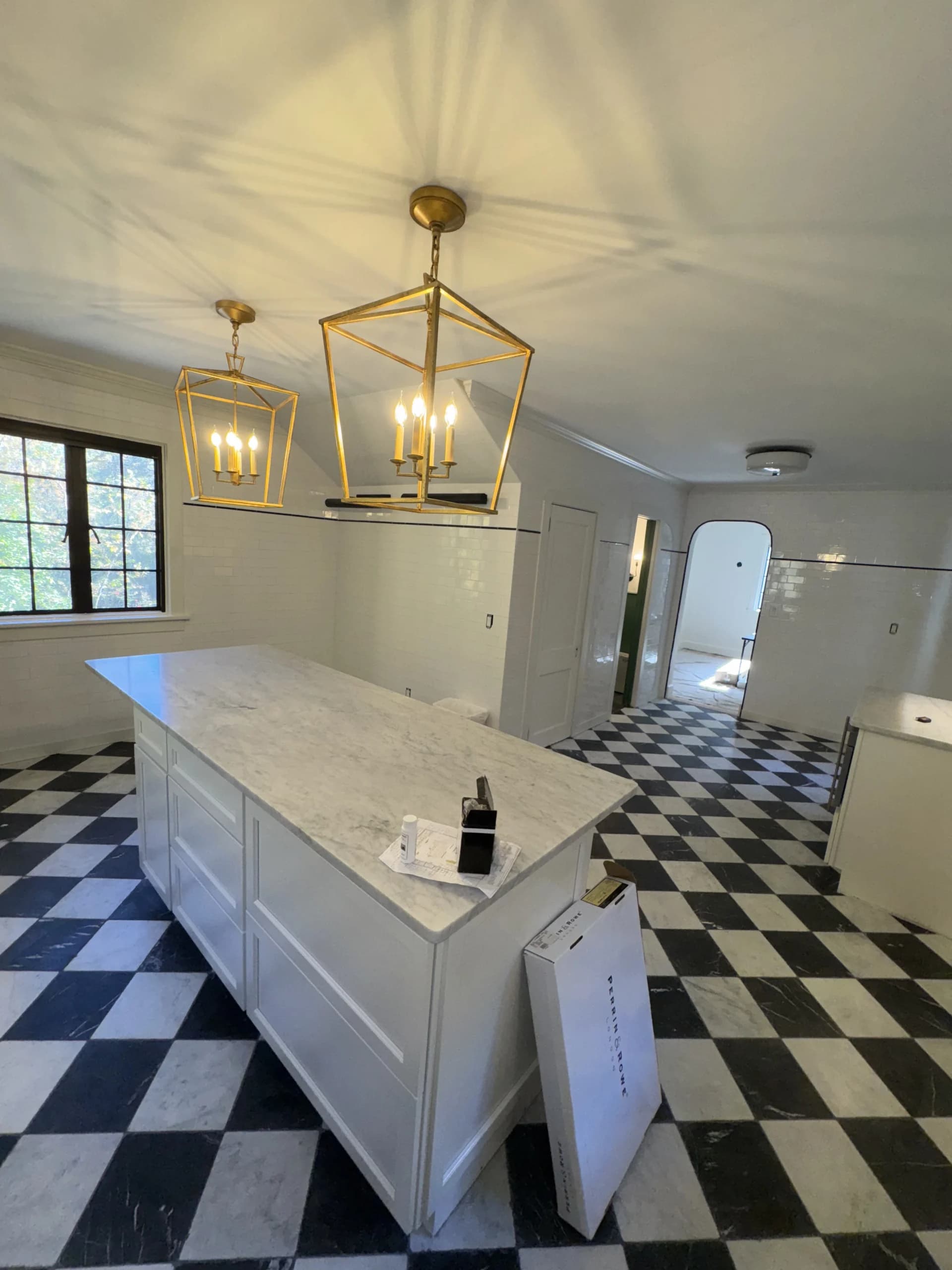 Kitchen with a marble island, brass lantern pendants and a black and white checkered floor - kitchen remodeling by Greater Homes Solutions LLC