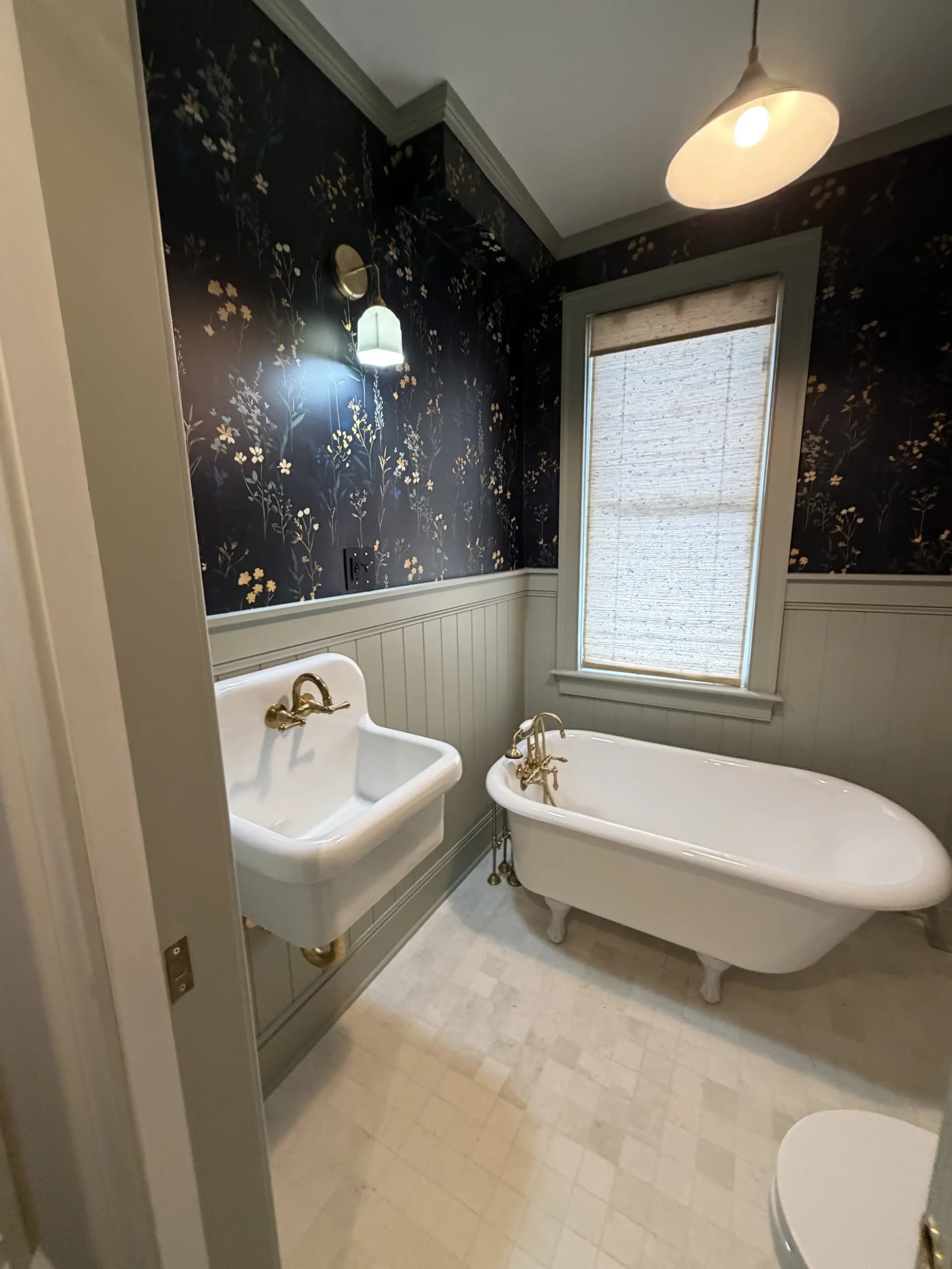 Bathroom with dark floral wallpaper, wainscoting, a clawfoot tub and a wall-mounted sink - bathroom remodeling by Greater Homes Solutions LLC