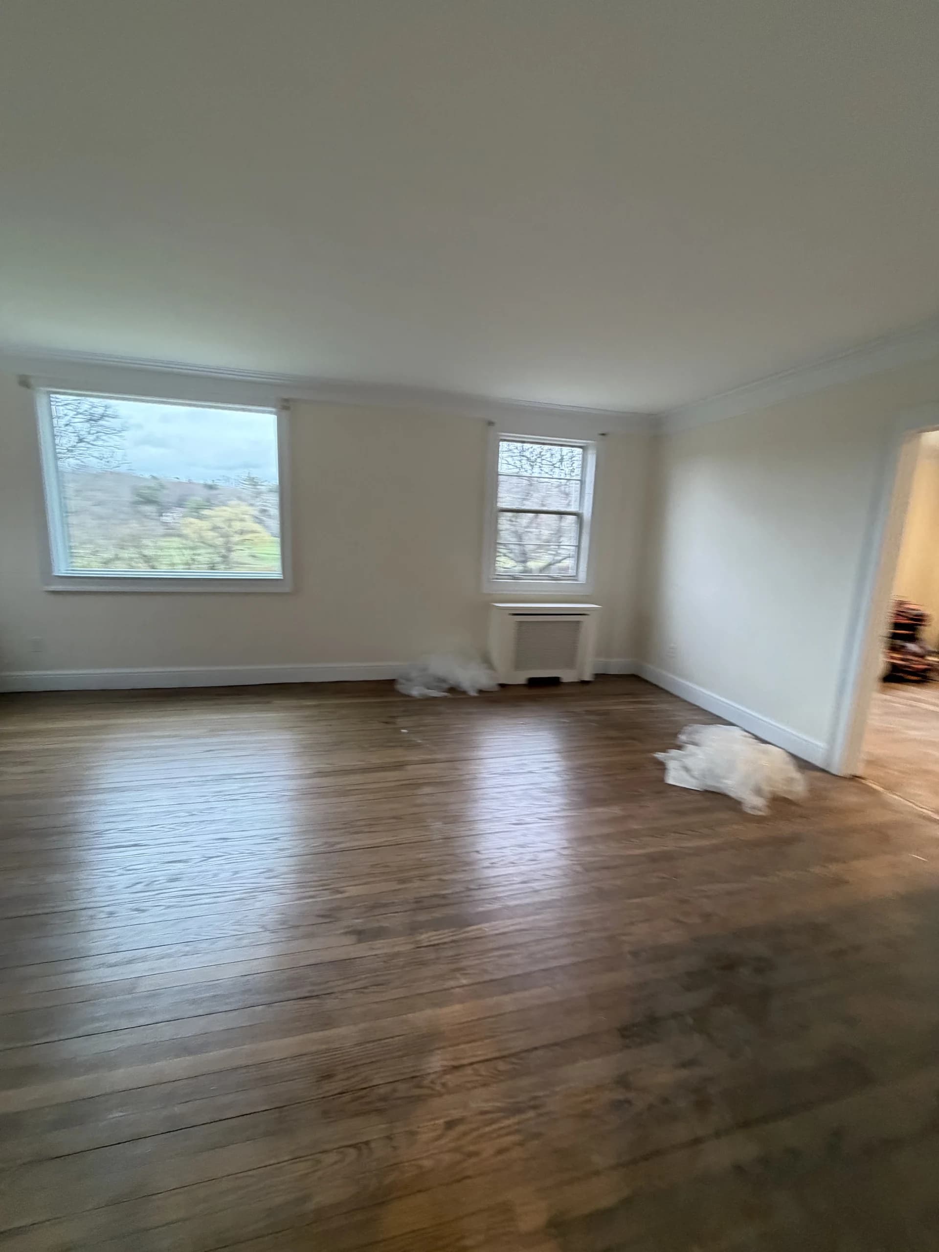 Sunlit empty room with refinished hardwood floors and freshly painted white walls - Greater Homes Solutions LLC