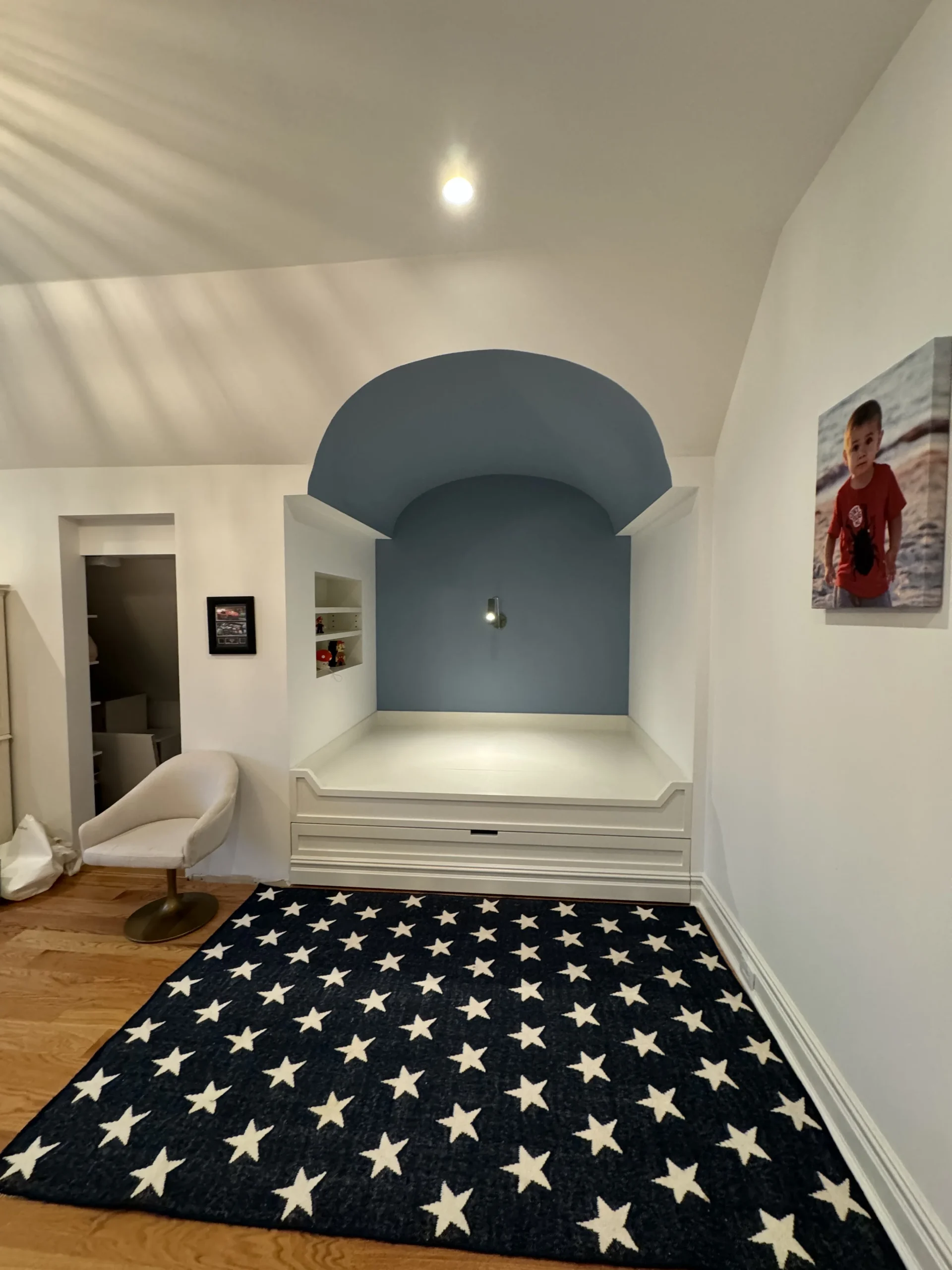 Child's bedroom with a blue arched reading nook and a star-patterned rug - interior painting by Greater Homes Solutions LLC