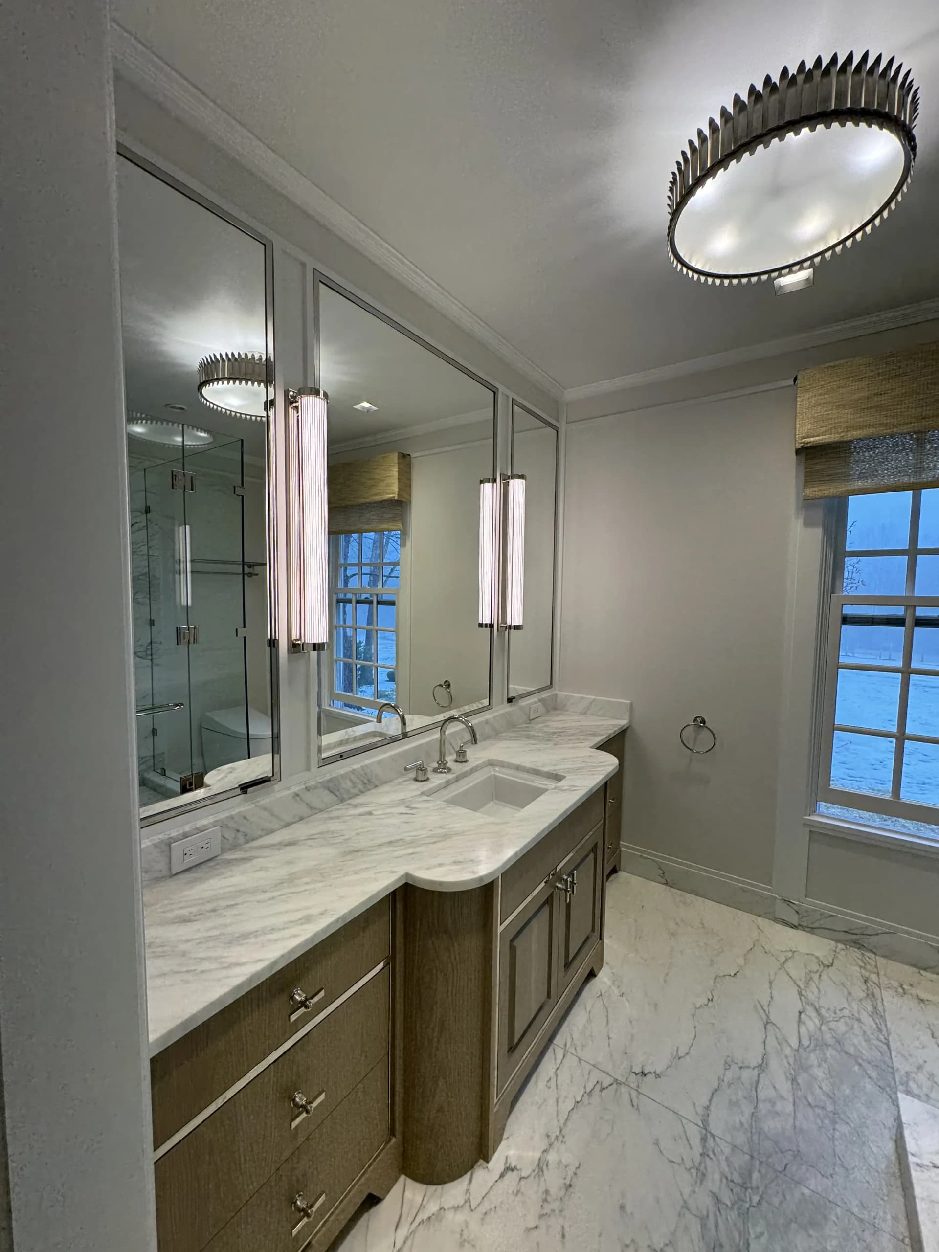 Bathroom vanity with a marble countertop, wood cabinets and a full-width mirror - bathroom remodeling by Greater Homes Solutions LLC