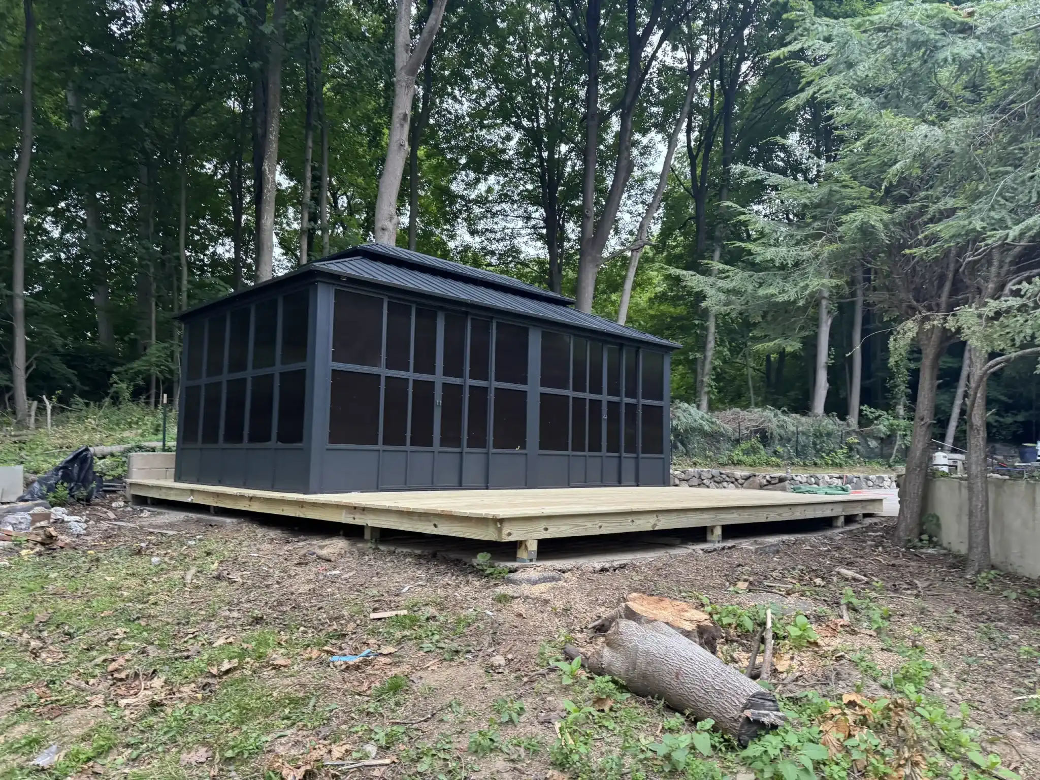 Black screened gazebo on a new wood deck platform in a wooded backyard - built by Greater Homes Solutions LLC