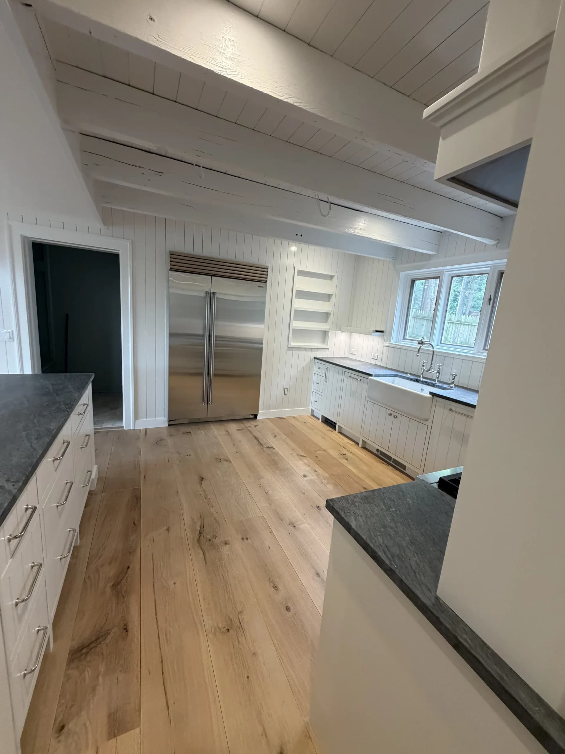 Kitchen with a slate-topped island, a stainless refrigerator and white shaker cabinets - kitchen remodeling by Greater Homes Solutions LLC